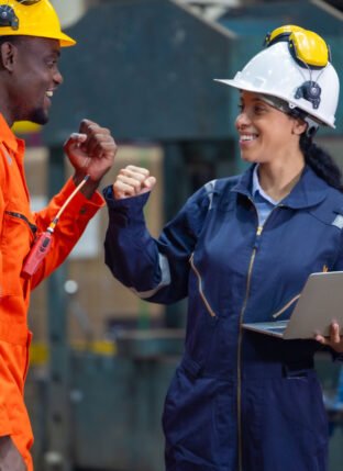 Male locomotive diesel engineer and female supervisor celebrate successful completion of crucial project in a railway maintenance facility, showcasing teamwork and achievement in industrial settings.