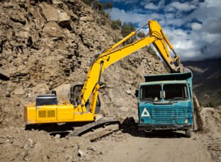 Road construction in mountains Himalayas - excavator and truck.  Lahaul valley, Himachal Pradesh, India